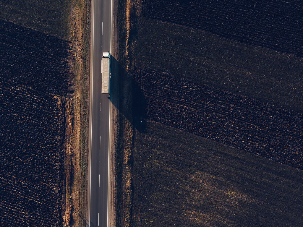 Aerial view of freight transportation truck on the road through countryside