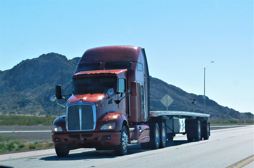 flatbed truck with no load on empty road